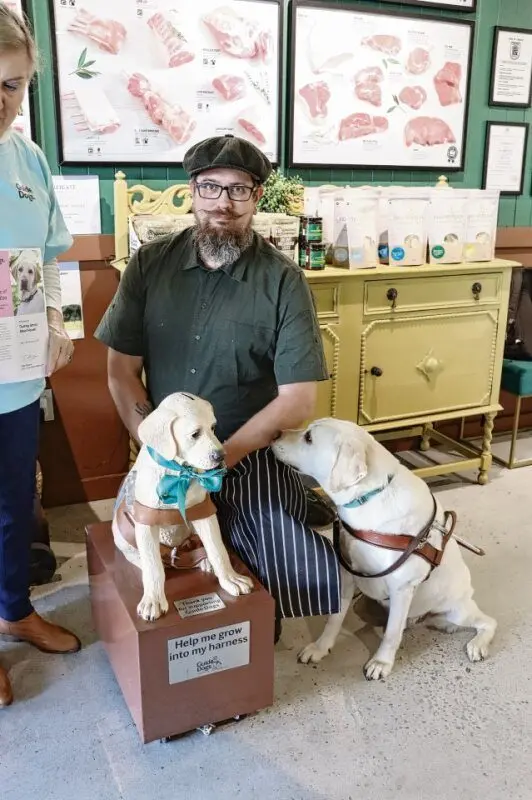 Dubbo butcher Nathan Gunter, who owns Darling Street Meat House, supports the Guide Dogs with a donation box in his store. He\\'s pictured here with local guide dog, Zeek. Photo: Dubbo Photo News.