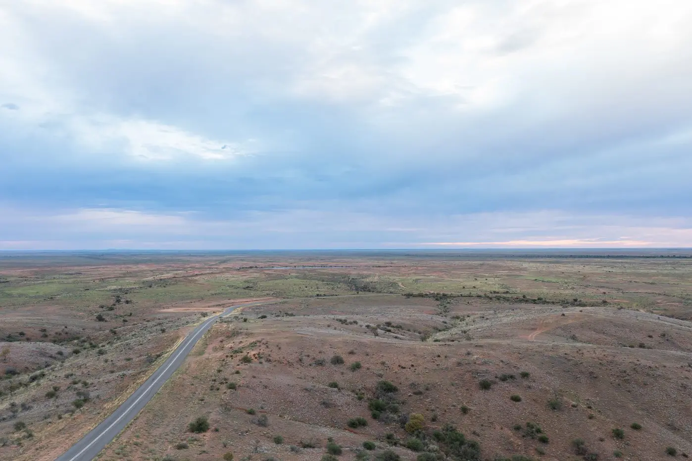 The view looking west over the Mundi Mundi Plains, 30km west of Broken Hill, showing an already sealed section of road. A 2.5km section that is currently unsealed will be upgraded over the next three months. Photo: AAP/Stuart Walmsley