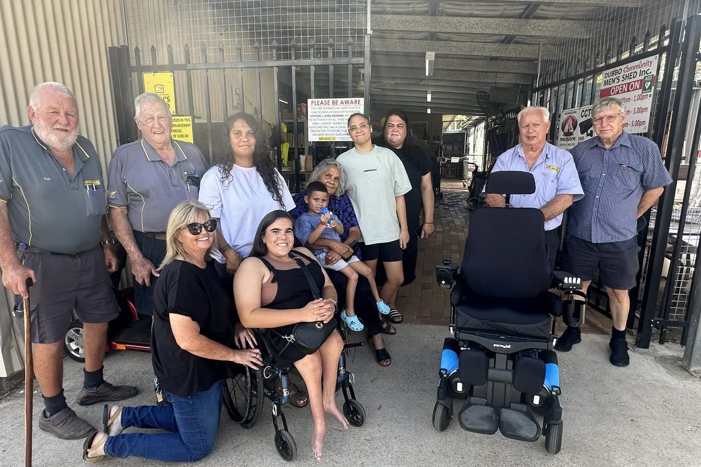 Tijuana Keed (fifth from left) received the state-of-the-art motorised wheelchair at the Dubbo Community Men\\u2019s Shed on March 13. Photo: Dubbo Photo News