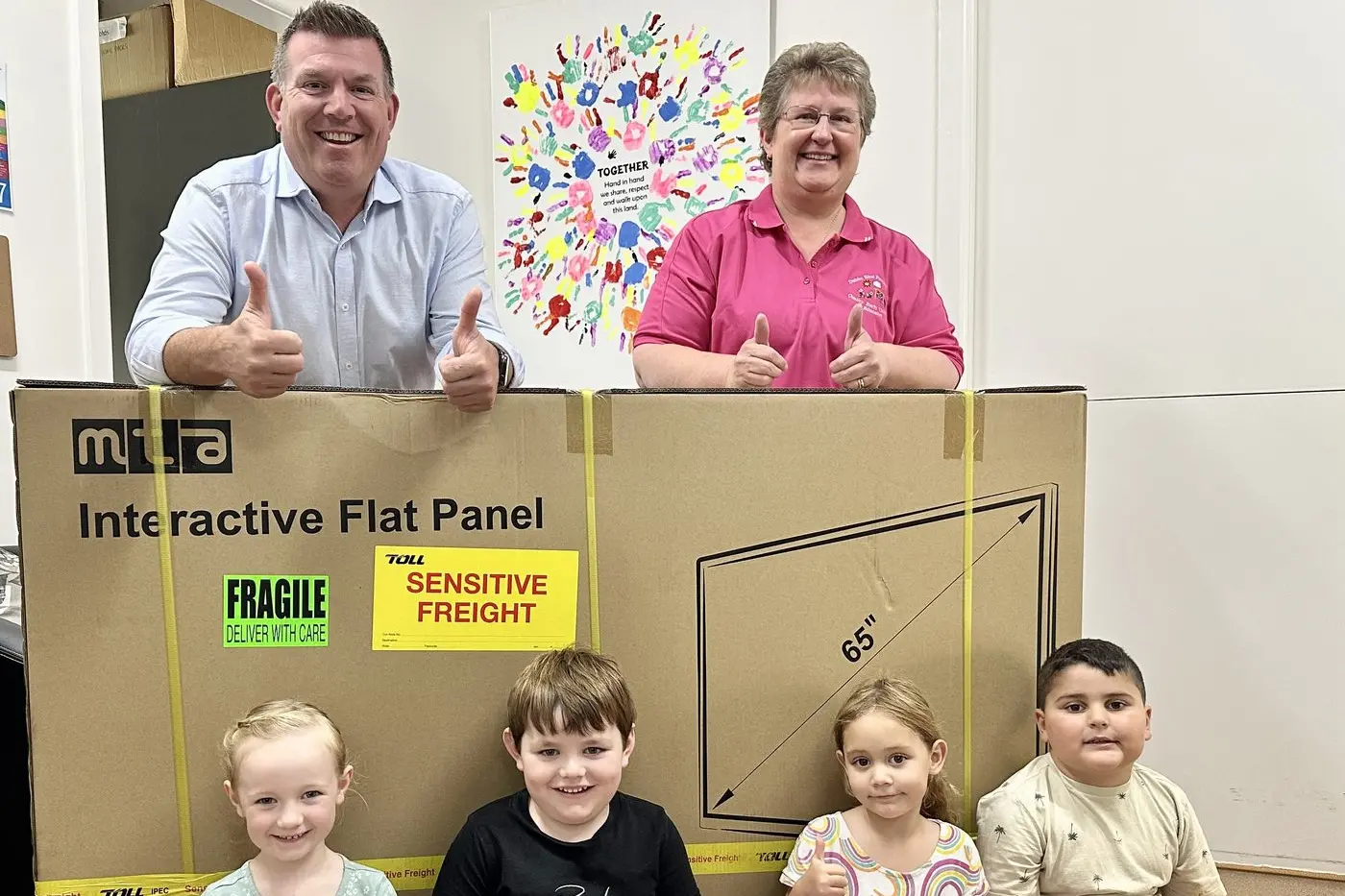 Thumbs up for whiteboards for smarter learning at West Dubbo: Member for Dubbo Dugald Saunders, Dubbo West Preschool director Kathryn Albert, and some happy pupils with their new smart-board. Photo: Supplied.