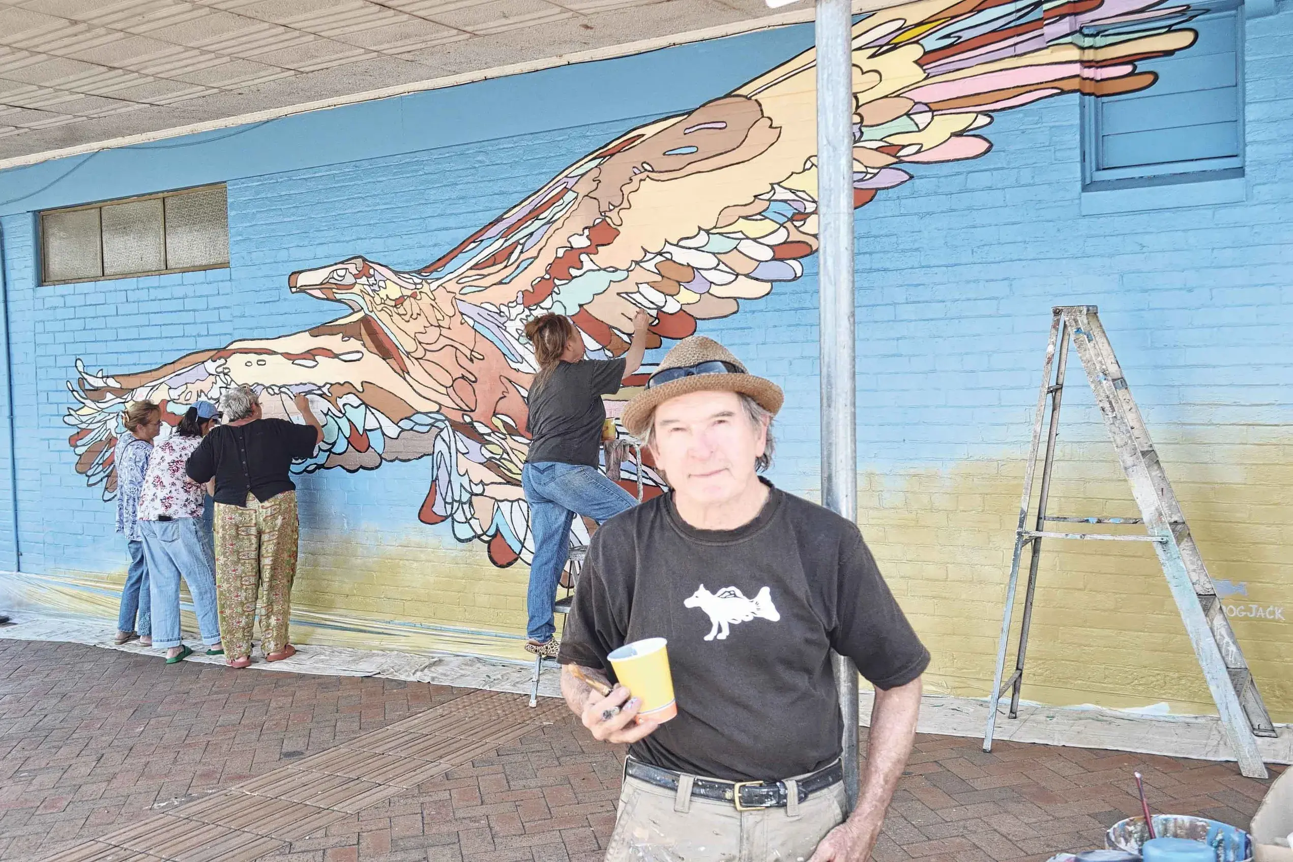 <p>Artist Jack Randell stands before the mural the community helped make. Photos: Colin Rouse</p>\\n